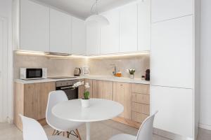a white kitchen with a white table and chairs at Acropolis Urban Life in Athens