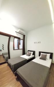 Pokój z dwoma łóżkami i znakiem na ścianie w obiekcie ROOM Ijen Hostel w mieście Banyuwangi