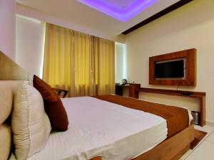 a hotel room with a bed and a television at Hotel Divine Residency by VARSHRI in Haridwār