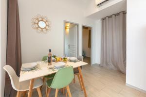 a dining room with a white table and green chairs at Mon Rêve, charmant cabanon les pieds dans l'eau à la Madrague, confortable et lumineux in Hyères