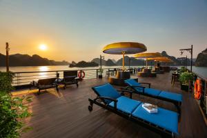 una terraza con sillas y mesas sobre el agua en Nostalgia Halong Cruise en Ha Long