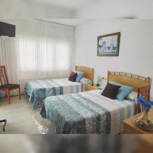 Habitación de hotel con 2 camas y TV en Hostal La Llave, en Mave