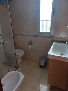 een badkamer met een wastafel, een toilet en een raam bij Appartement proche mer in Santiago de la Ribera