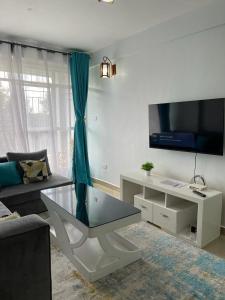 a living room with a coffee table and a tv at Zoe Homes Country Cottages 1bedroom Green square in Kericho