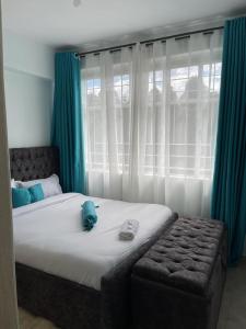 a bedroom with a large bed with blue curtains at Zoe Homes Country Cottages 1bedroom Green square in Kericho