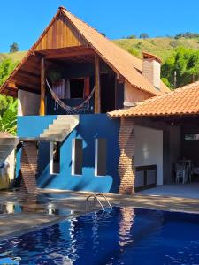 a house with a blue wall and a swimming pool at Chalé Mantiqueira in Piranguçu
