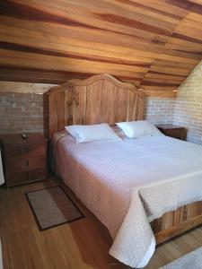 a bed with a wooden headboard in a room at Chalé Mantiqueira in Piranguçu
