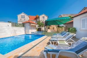 una fila di sedie a sdraio accanto alla piscina di Family friendly house with a swimming pool Skrip, Brac - 17345 a Postira (Postire)