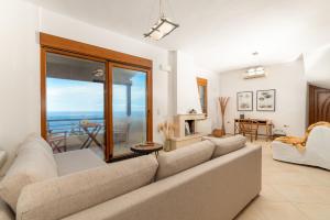 a living room with a couch and a view of the ocean at Vitamin Sea Panoramic Villas in Agia Pelagia