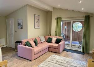 a living room with a pink couch and a window at Bluewood Lodges in Kingham