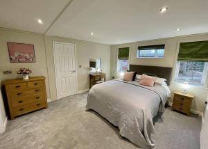 a bedroom with a bed and a dresser and windows at Bluewood Lodges in Kingham