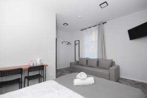 a white bedroom with a bed and a couch at Zefiro Seredyńskiego in Gdańsk