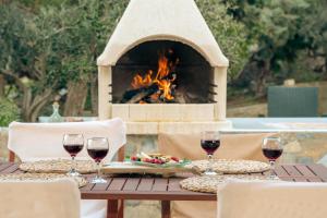 a table with wine glasses and a fireplace at Vitamin Sea Panoramic Villas in Agia Pelagia