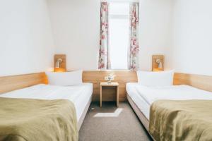 two beds in a room with a window at Hotel Andres in Bamberg