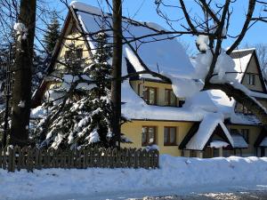 a house covered in snow next to a fence at Willa Jagiellonka apartamenty w centrum, parking in Zakopane