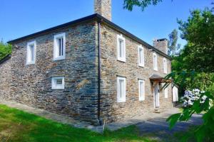 un antiguo edificio de ladrillo con ventanas blancas y flores en Casa La Falca en Ortigueira., en Santa Marta de Ortigueira