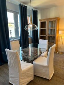 comedor con mesa de cristal y sillas blancas en Ferienwohnung Landhaus 44 Citynah, toskanischer Flair, en Hamburgo