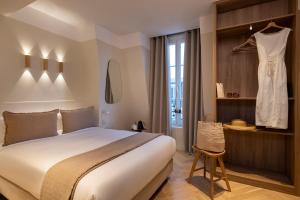 a bedroom with a bed and a dress hanging on a wall at Hôtel Le Daum in Paris