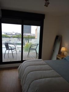 1 dormitorio con 1 cama y balcón con 2 sillas en A estrenar en Punta Carretas en Montevideo