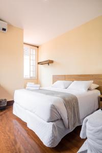 1 dormitorio con 2 camas grandes con sábanas blancas en Pousada Catedral, en Petrópolis