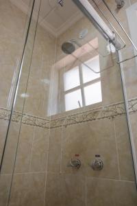 a shower with a glass door and a window at Pousada Catedral in Petrópolis