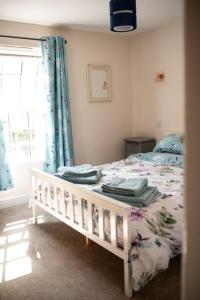 1 dormitorio con 1 cama con cortinas azules y ventana en Braybrooke Cottage, Saffron Walden en Saffron Walden