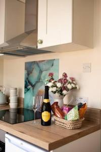 a bottle of wine and a basket of food and a wine glass at Braybrooke Cottage, Saffron Walden in Saffron Walden
