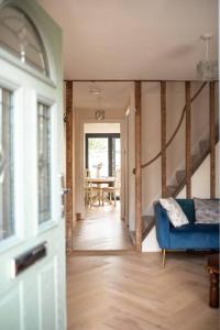 a hallway with a blue couch and a dining room at Braybrooke Cottage, Saffron Walden in Saffron Walden