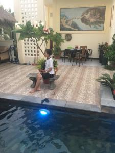 a woman sitting on a bench next to a swimming pool at B&B Verger Vannary 