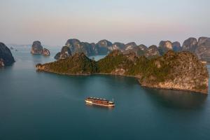 un barco en un gran cuerpo de agua con montañas en Nostalgia Halong Cruise, en Ha Long