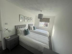 a white bedroom with two beds and a window at Alma Court Retreat Freshwater IOW in Freshwater
