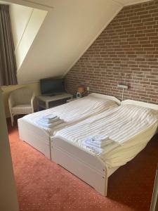 Ce lit se trouve dans une chambre dotée d'un mur en briques. dans l'établissement Recreatiecentrum de Kluft, à Ossenzijl