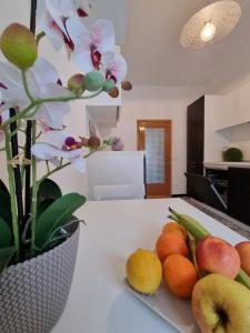 un piatto di frutta su un bancone della cucina con un vaso di fiori di Appartamento al Centro Storico di San Marino a San Marino