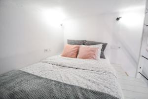 a white bedroom with a bed with two pink pillows at LION apartments in Krakow