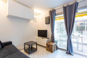 salon z kanapą, telewizorem i oknem w obiekcie Chez Claude - Joli studio cabine climatisé avec parking et piscine w mieście La Grande-Motte