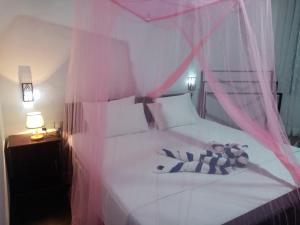 ein Schlafzimmer mit einem weißen Bett mit rosa Vorhängen in der Unterkunft Peacock Garden in Tangalle