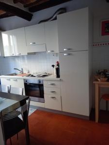 Una cocina blanca con gabinetes blancos y una mesa y un tableablish en Rocci al 17, en Montalcino 13 fotos más