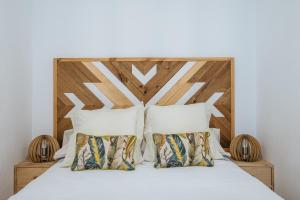 Bett mit einem Kopfteil aus Holz und 2 Kissen in der Unterkunft Apartamento exclusivo junto a la catedral de Sevilla in Sevilla