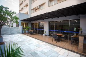 um pátio exterior com mesas e cadeiras num edifício em Gelps Hotel em Rio Verde