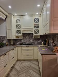 a kitchen with white cabinets and marble counter tops at Luxury Stefan cel mare Apartment in Chişinău