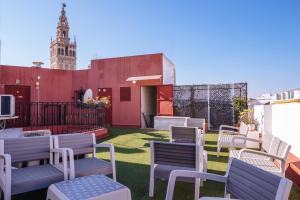 ein Balkon mit Stühlen und ein Gebäude mit einem Uhrenturm in der Unterkunft Ático lujo junto a la catedral. Giralda in Sevilla