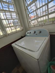 a washing machine in a bathroom with two windows at A Jewel of A Chalet in Roseau