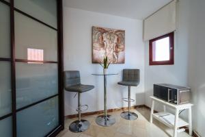 ein Wohnzimmer mit 2 Hockern und einem TV in der Unterkunft Ático lujo junto a la catedral. Giralda in Sevilla