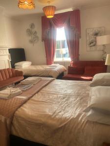 a room with two beds and a couch and a window at Parlors Hall Hotel in Bridgnorth