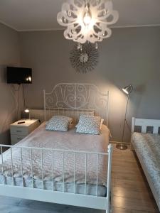 1 dormitorio con cama blanca y lámpara de araña en Anna, en Czarny Młyn