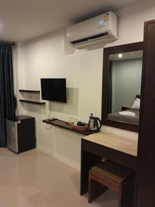 Habitación con escritorio, TV y espejo. en Rawai Sea Beach en Phuket