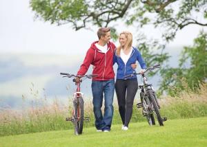 a man and a woman walking two bikes in a field at Nunland Hillside Lodges 