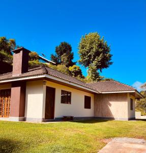a small white house with a grass yard at Casa para Descanso in Campos do Jordão