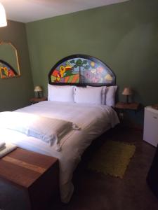 a bedroom with a large bed with a painting on the wall at Alive Eco Hut Pousada in Monte Verde