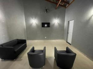 a room with two chairs and a tv on a wall at Casa De Temporada Eldorado in Olímpia